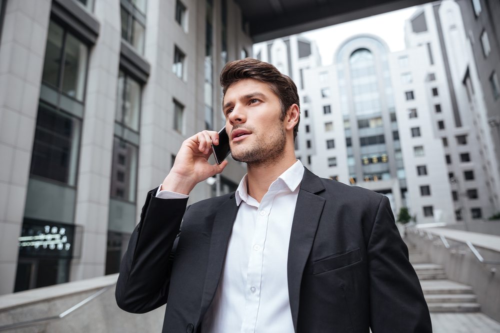 Business person outdoors in city setting talking on a mobile phone.